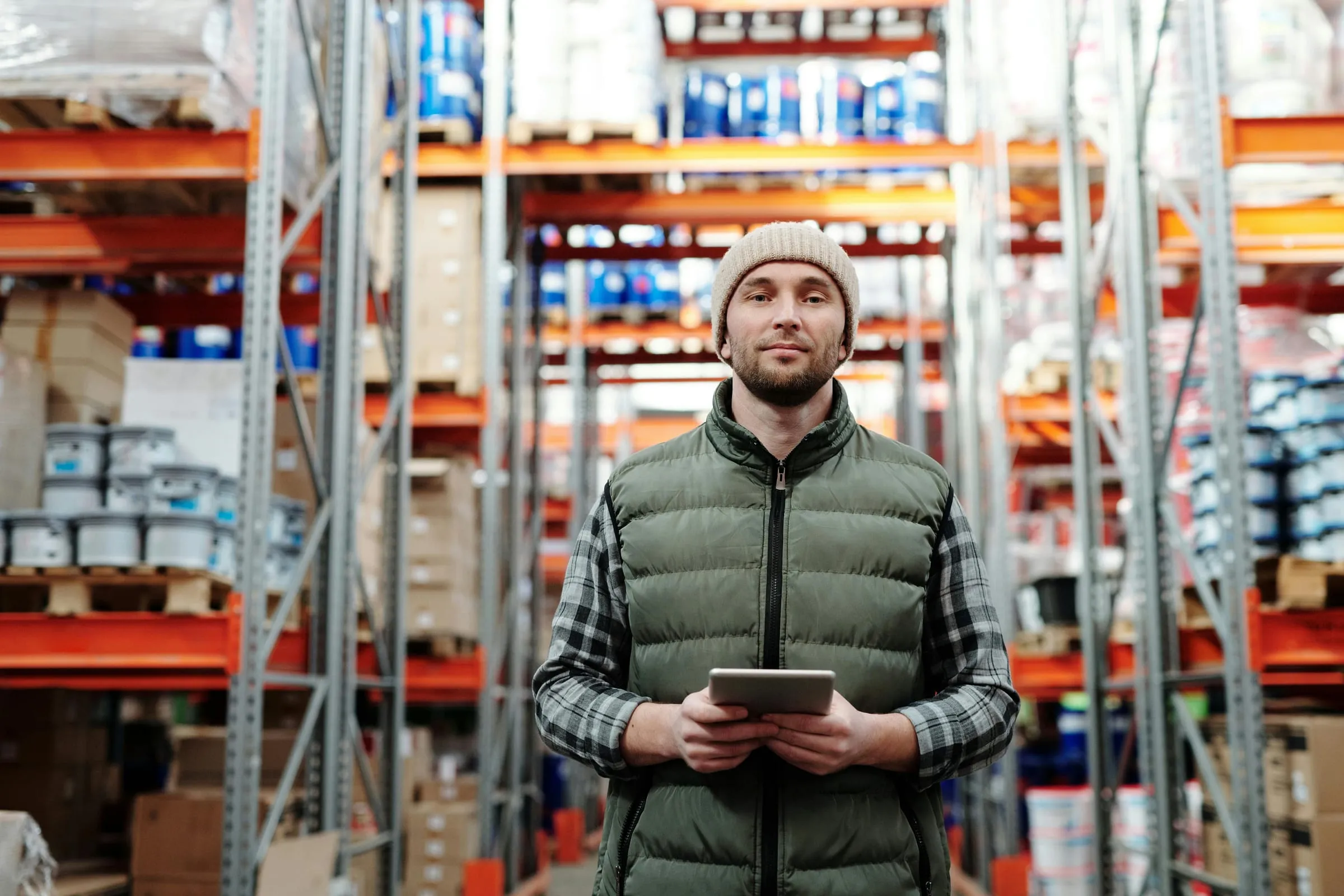 A warehouse worker holding a tablet between the racks